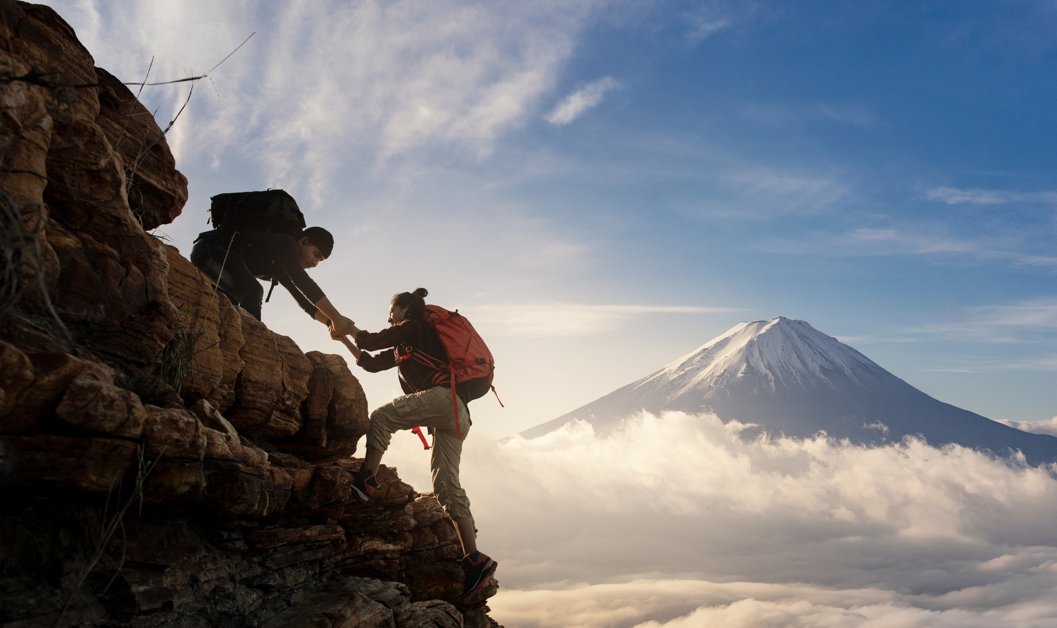 Group of Asia hiking help each other silhouette in mountains with sunlight.