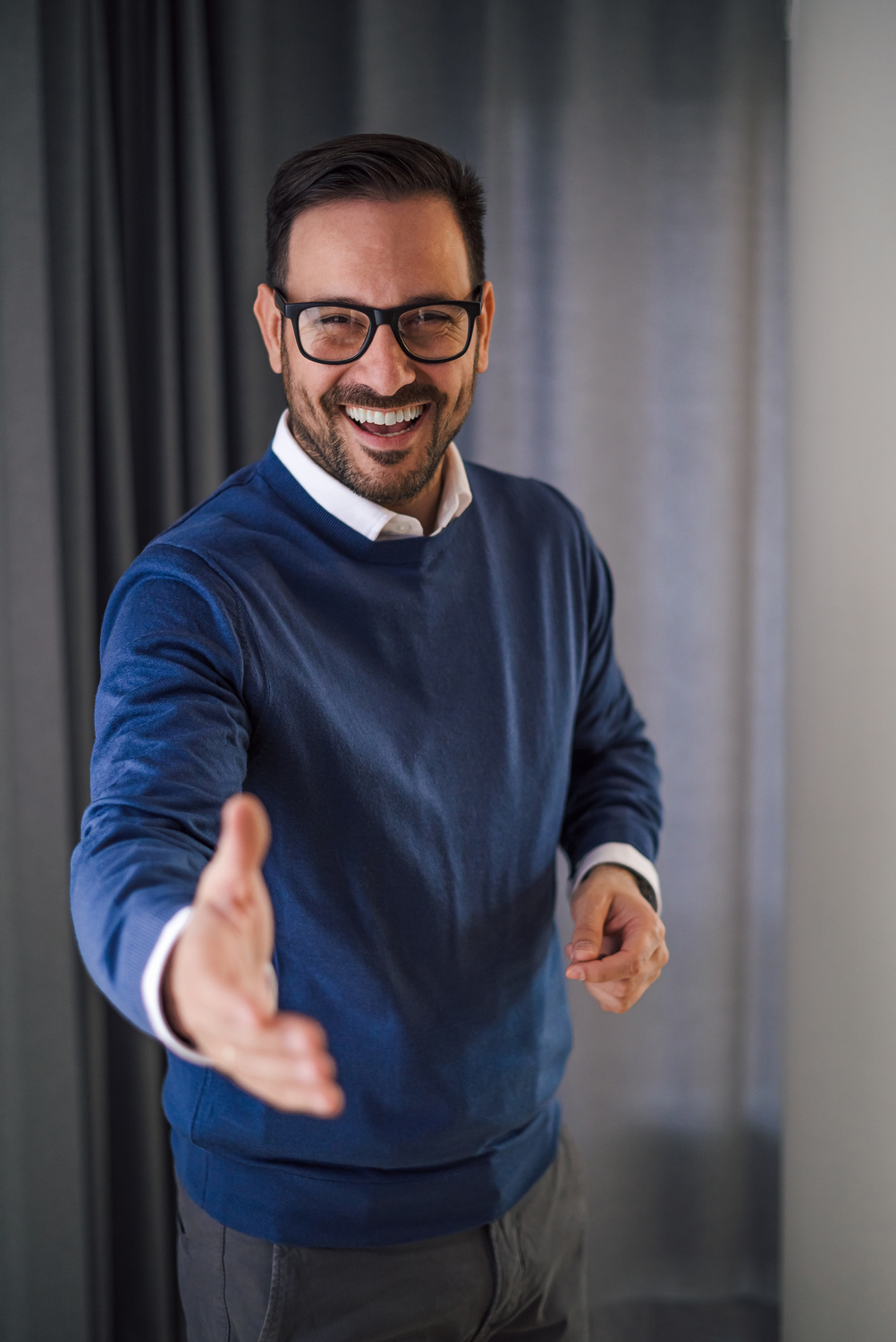 Enthusiastic young adult manager, extending his hand to the camera. Handshake.